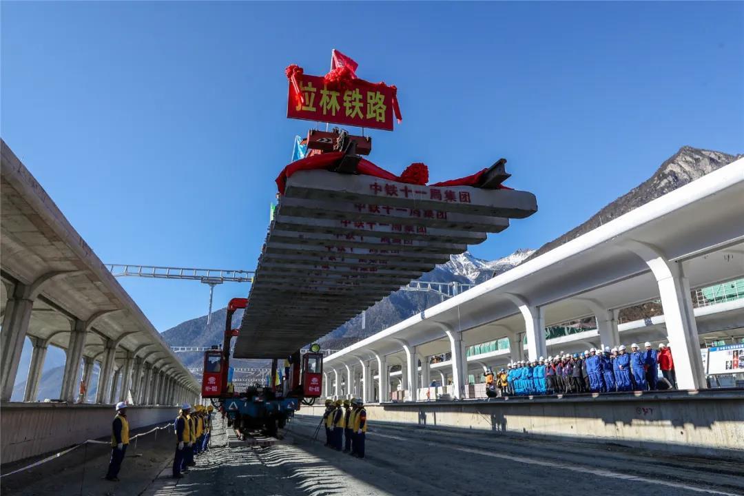 2020年12月31日，在西藏林芝市川藏鐵路拉薩至林芝段（拉林鐵路）鋪軌現場，隨著作業人員將最后一排長25米的軌排緩緩的鋪設在林芝站正線路基上，標志著拉林鐵路全線軌道鋪通，為鐵路后續建成通車打下堅實基礎。圖為最后一排軌排鋪設現場。