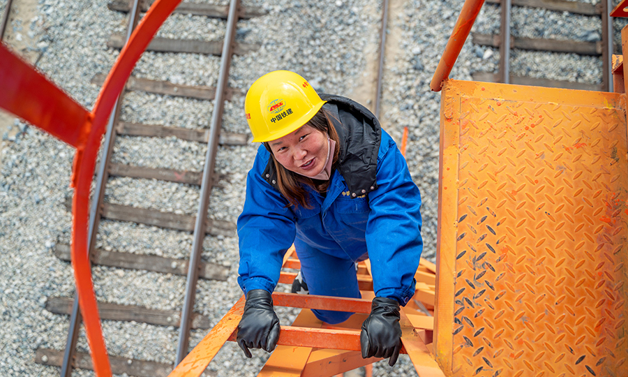 拉林鐵路女工班是一個有著優良傳統的班組，其前身是青藏鐵路女工班，曾經獲得全國五一巾幗獎、全國三八紅旗集體榮譽稱號等，現任班長是曾經參加過青藏鐵路的賴軍超，目前班組內共有2人二次入藏，主要在軌排生產線上從事龍門吊司機的工作，他們將堅守在雪域高原，修建著進藏的新天路，在現青藏女工班的風采。圖為每一次移梁，袁芳都會爬上龍門吊，在10米左右的高空中操作。（丁慶濱 攝）