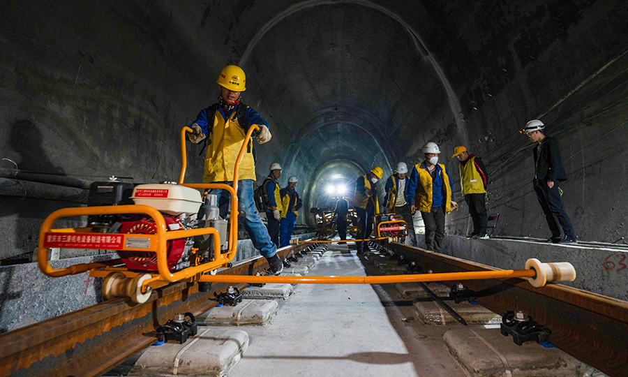 拉林鐵路是西藏首條電氣化鐵路，建成通車后將結束藏東南地區沒有鐵路的歷史，改善西藏鐵路網的布局和規劃，為西藏東部地區的經濟發展注入新的活力。目前，項目已完成正線鋪軌126.3公里，其中有砟109.5公里、無砟15.7公里，預計今年年底完成全線鋪軌任務。圖為施工人員正在對已鋪設好的軌道安裝扣件。