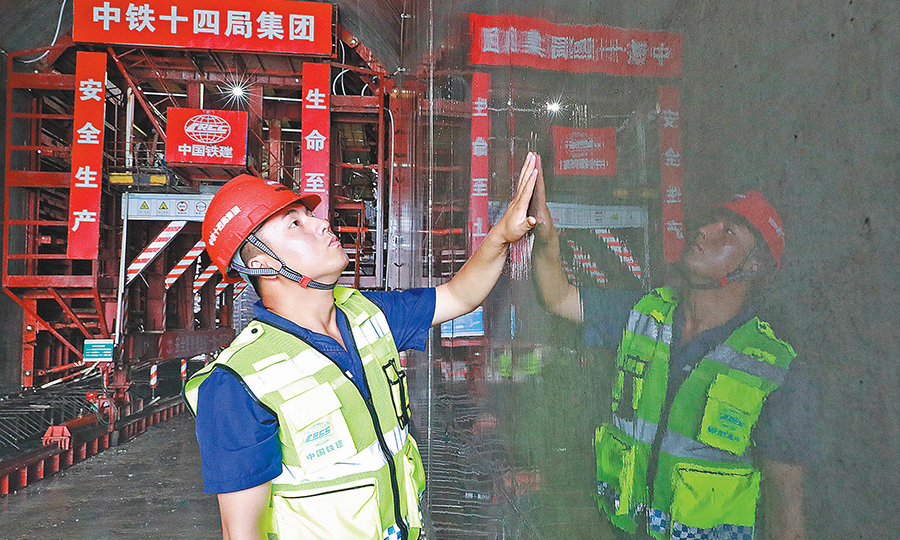 日前，中國鐵建所屬中鐵十四局二公司洛寧抽水蓄能電站項目部澆筑的第一倉清水鏡面混凝土揭開了神秘的“面紗”。圖為技術人員在查看混凝土養護效果。（王亮亮 攝）