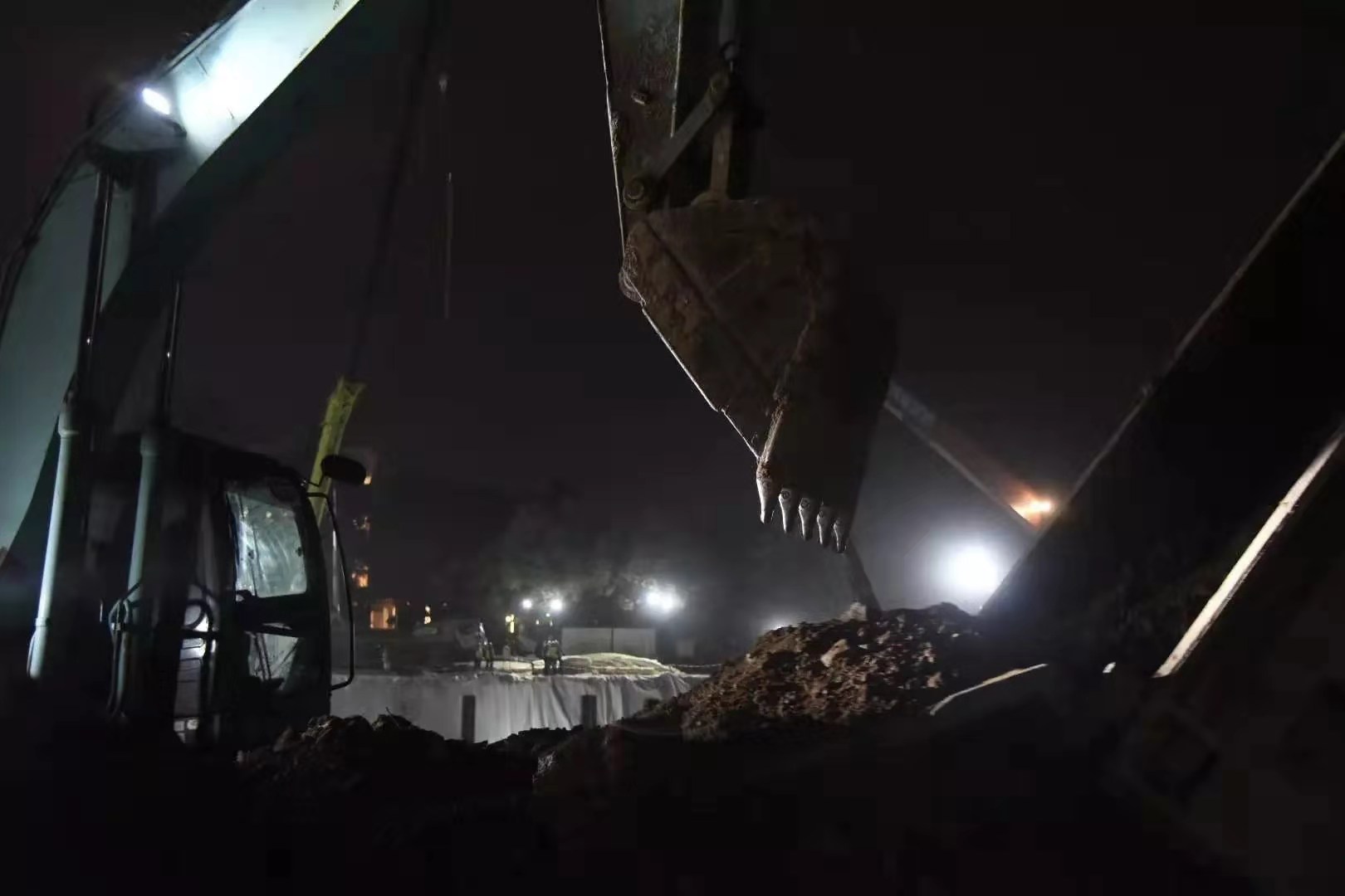截至2月1日，火神山醫院項目場地基礎施工全部完成。圖為2月1日20時，火神山醫院蓄水池，挖掘機協助卡車卸下剛運到泥土。