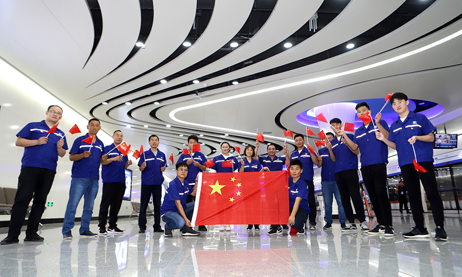 圖為建設者在北京大興國際機場地鐵線草橋站與國旗合影（范成濤 攝）