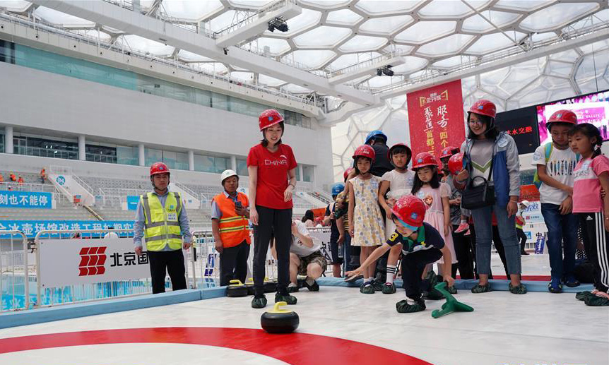 為滿足北京2022年冬奧會和冬殘奧會賽事需要，2018年12月26日，國家游泳中心“水立方”正式開始施工改造，改造后的國家游泳中心將在比賽大廳新增冰壺場地功能；同時在南廣場新增地下冰場，服務于群眾冰上健身和普及冰壺運動。國家游泳中心場館將于2020年7月完成場館永久設施改造任務，滿足舉辦冬奧會測試賽的需求。圖為6月2日，一名小朋友在改造中的國家游泳中心內的簡易冰壺場地體驗冰壺游戲。（新華社記者 鞠煥宗 攝）