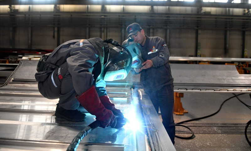 4月27日，周晶輝（右）與徒弟臧鐵軍一起研究改進高鐵車體焊接工藝。（新華社記者 張楠 攝）