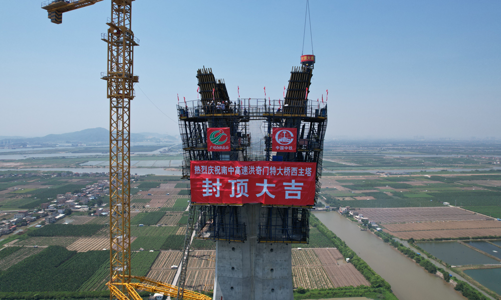 主塔采用全自動液壓爬模系統進行施工，在主塔兩肢合龍后逐漸向外傾斜展開，形成“花開”造型，這對液壓爬模軌道在空中進行換軌帶來了較大挑戰。項目部將直軌道優化為與主塔線型契合的弧形軌道，在縮短每個節段施工周期的同時，也有效保障了塔柱高空施工作業安全。圖為洪奇門特大橋西主塔封頂。