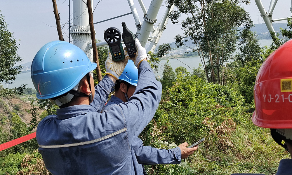在500千伏線路帶電作業前，廣東電網公司作業人員用測風儀和智能手機測試現場風力風速。
