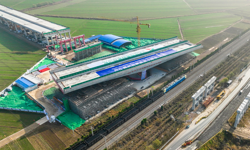 跨京滬鐵路轉體橋上部結構采用預應力混凝土T構，跨徑組合為（68+68）米，下部結構主墩采用“V”型空心墩設計，整幅橋梁全寬38.33米，轉體重量高達25680噸，主承臺深基坑開挖處臨近繁忙干線京滬鐵路，距路基坡腳線最近處僅有15米，臨近鐵路基坑開挖深度10余米，施工過程復雜、精度要求高。圖為轉體橋轉體中。