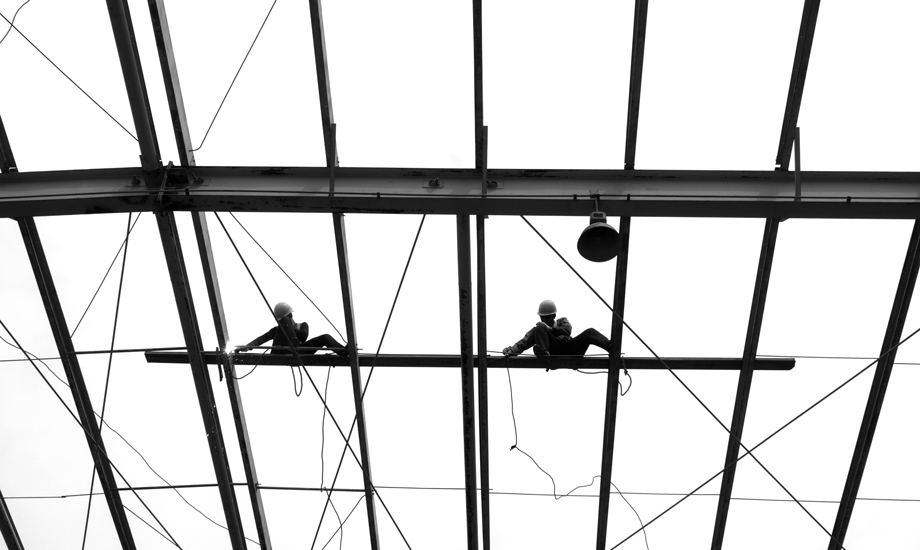 在高約十四、五米的屋脊上，鋪板工左右丈量、分毫不差，通過自己耐心、細致的工作，抒發著“勞動最美麗”的壯志豪情。（作者：崔棟）